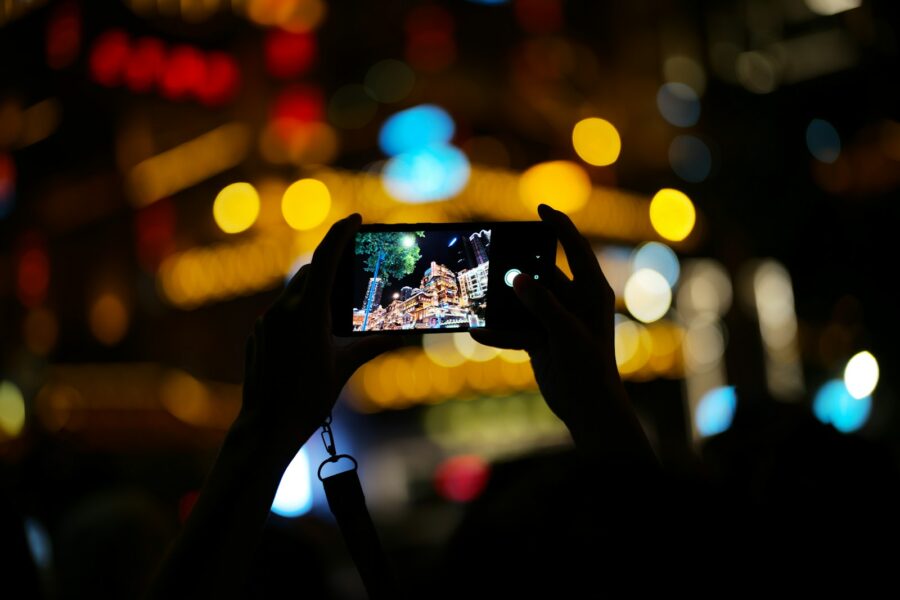 Hand holding smartphone taking photo city night