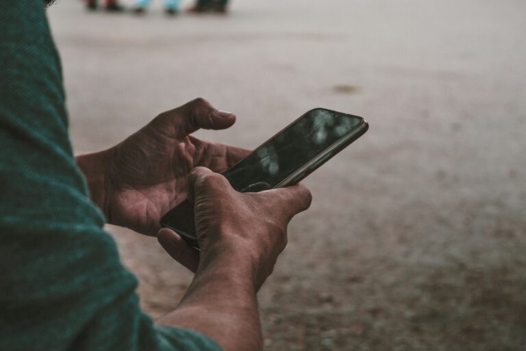 Hand holding mid-range smartphone outdoors