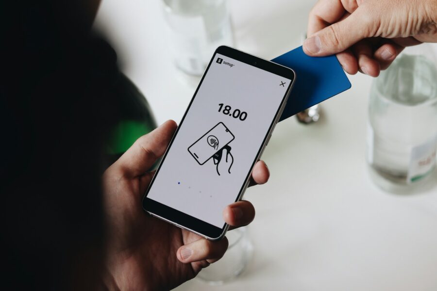 Hand holding smartphone over contactless payment terminal